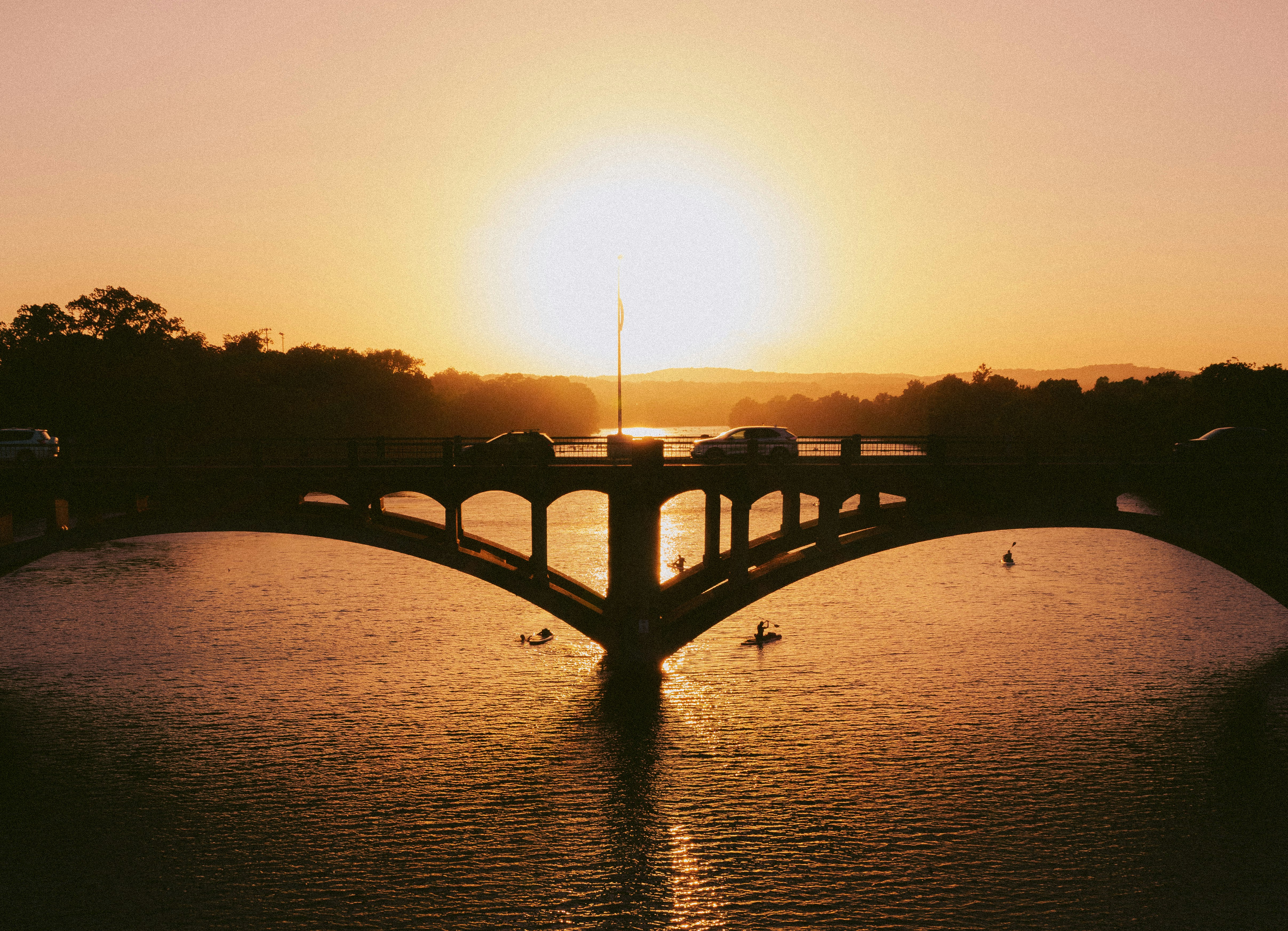 silhouette of bridge over body of water during sunset